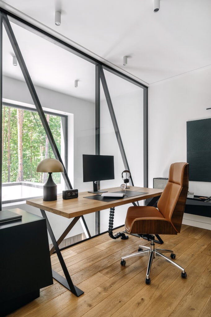 A modern home office with sleek furniture and a view of the forest during daylight hours